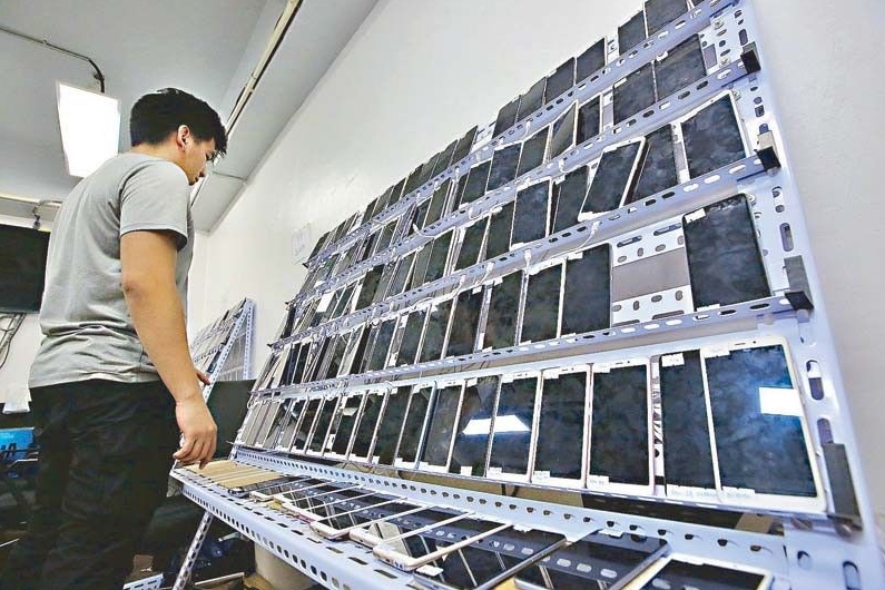 A law enforcer inspects a bank of cell phones during a raid on a Philippine offshore gaming operator in Pasay City on Tuesday night